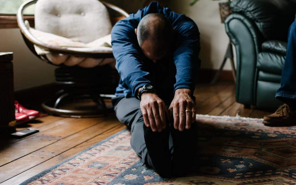 Mand strækker sine muskler ud på stuegulvet
