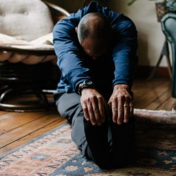 Mand strækker sine muskler ud på stuegulvet